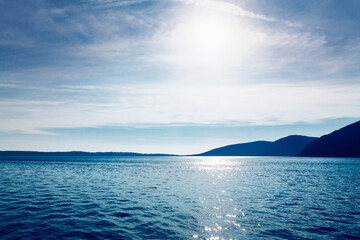 Sun over the blue sea and mountains . Blue tide and islands