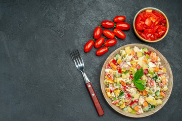 top view of vegetable salad with tomatoes and fork on side and free space for your text on dark grey background