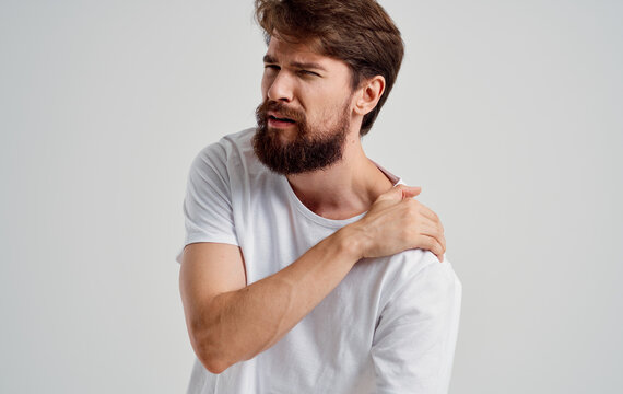 bearded man touching shoulder with hand pain dislocation medical intervention