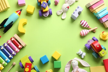 Frame made of different toys on green background, flat lay. Space for text