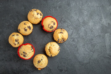 Overhead view of freshly baked small cupcakes with chocolates on dark background