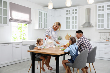 Happy family having breakfast together at table in modern kitchen