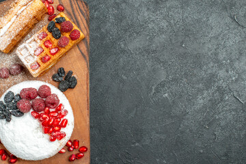 top close view tart and waffles with berries on wood cutting board on dark background with copy space