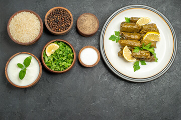 top view bowls with rice natural yogurt parsley pepper black pepper salt dolma on white plate on dark background with copy space