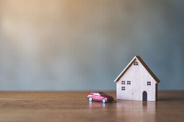 Obraz na płótnie Canvas A car figure model and wooden house model on the table