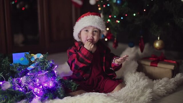 a child in red clothes is sitting waiting for the new year. the concept of celebrating Christmas at midnight. holiday costume