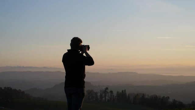 photographer taking picture of beautiful dusky landscape behind a transmission mast
