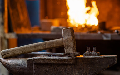 Blacksmith hammer on the anvil against the background of fire