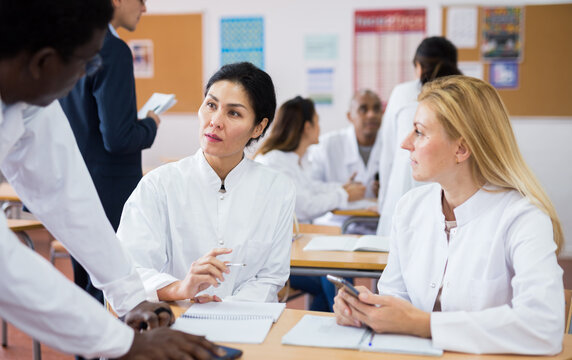 Portrait of adult medical students divided into small groups to discuss course material in classroom