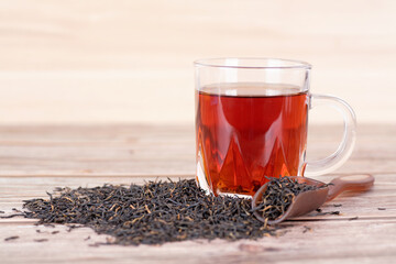 A cup of black tea and scattered tea leaves