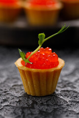 Appetizing tartlet with red caviar and microgreen decor. Holiday concept. Close-up.