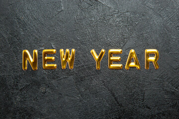 Horizontal view of greeting golden text New Year on dark background