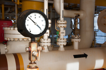 Closeup of manometer, measuring gas pressure. Pipes and valves at industrial plant.