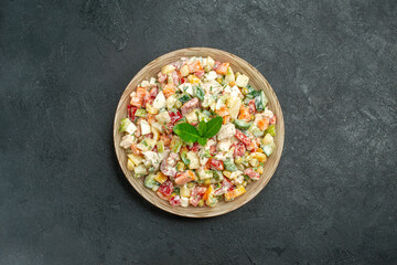 top view of bowl of vegetable salad in the center with green on it on dark green background