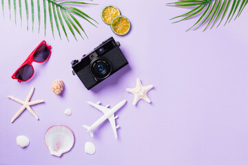 Top view flat lay mockup of camera films, airplane, sunglasses, leaves, starfish beach traveler accessories on a purple background with copy space, Business trip, and vacation summer travel concept