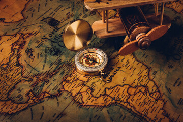 Old compass discovery and wooden plane on vintage paper antique world map background, Retro style cartography travel geography navigation, Columbus Day concept