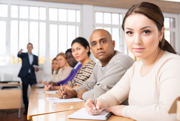 Young woman sitting at desk in classroom working during lesson at adult education class