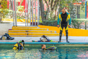 Diving class teacher giving instructions to his students from outside the pool