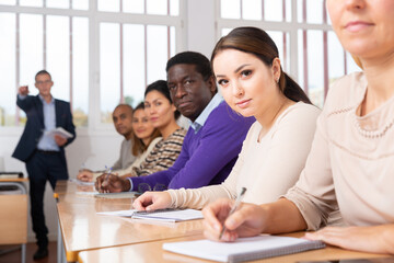 Portrait of positive woman sitting in class working during group business training