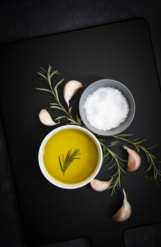 Olive oil, salt flakes, garlic cloves and rosemary.