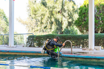 Naklejka premium diver coming out of the water by the stairs of the pool after his diving class