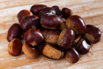 Obraz premium Closeup of pile of peeled edible chestnuts on wooden table ready for roasting..