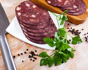 Close up of Spanish smoked blood sausage on white plate on wooden table