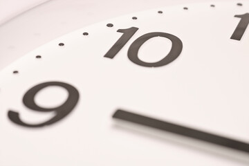 Dial of an analog Watch close up. Time 08:55. White dial, black numerals. Sepia toned image.