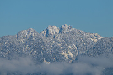 majestic mountain range covered with thin layer of snow above the cloud under blue sky