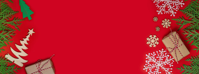 Merry Christmas and Happy New Year greeting card. Christmas background with gifts and green fir branches. Christmas holidays composition on red background with copy space. Flat lay. Long wide banner