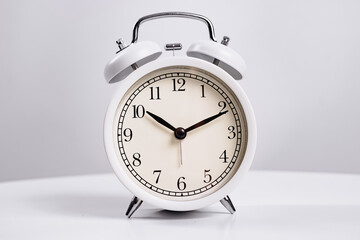 the white alarm clock is ringing. the concept of early morning rises.