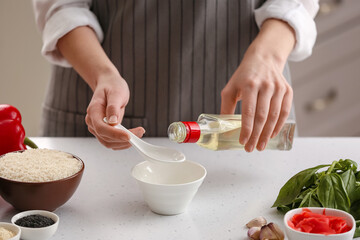 Obraz na płótnie Canvas Woman preparing sauce with rice vinegar in kitchen
