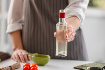 Woman with bottle of rice vinegar in kitchen