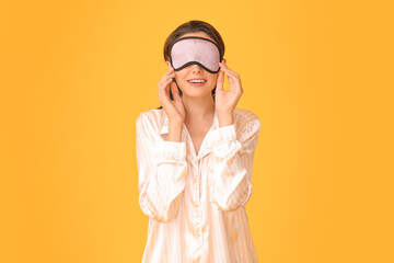 Portrait of young woman in sleep mask on color background