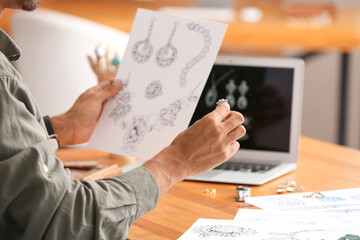 Male jewelry designer with sketches working in office, closeup