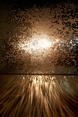 A wall with gold sequins, glare on the floor. Empty space, glamorous chic.