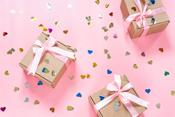 Pink gift boxes with heart shape confetti on pink background
