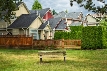 Old wooden bench in a park are in front of residential houses