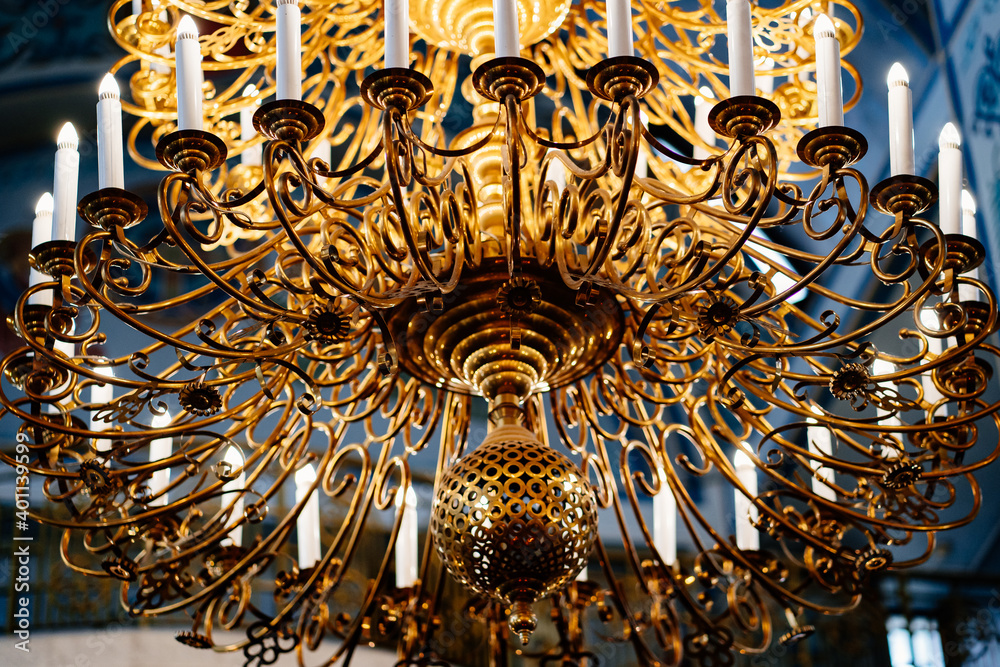 Poster beautiful large gold chandelier candle holder on the ceiling in the Church. 