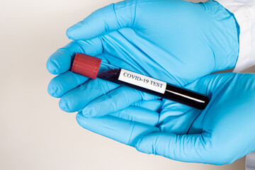 A doctor or lab technician wearing a gloves is holding a blood test tube with the inscription coronavirus test. COVID-19 Diagnostics, Rapid Test, SARS-CoV-2 Virus Detection