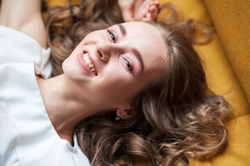 Fototapeta premium A woman is lying on a yellow sofa. Smile.
