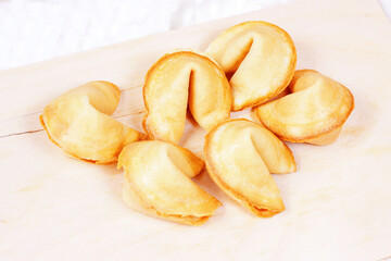 Fresh baked yellow Chinese fortune cookies on light background.