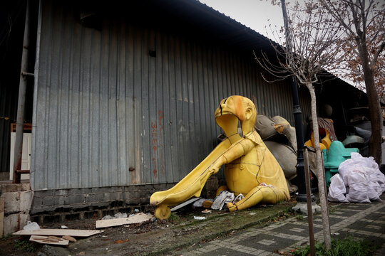 An old, yellow and broken plastic slide from a playground ekes out a life with other bulky waste on the side of the road in Istanbul. It shows a man with a wheelbarrow who has opened the m&uacute;nd. Childre