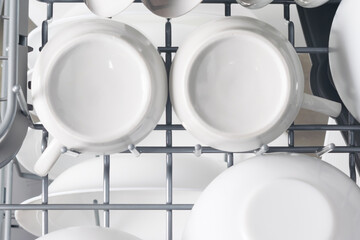 white set of dishes in dishwasher baskets, top view, close-up