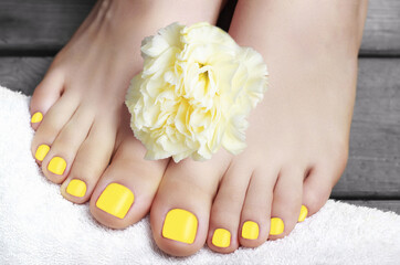 Yellow pedicure with flower on gray wooden background, top view © TATIANA KIM
