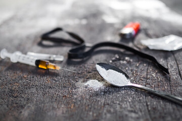 Amphetamine on spoon and in syringe with black  rubber band on dirty dark cement floor. Addictive substance, narcotic, Illegal thing, dangerous drug concept.