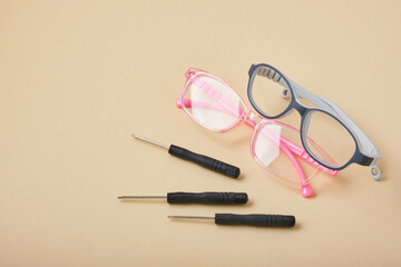 Obraz na płótnie Canvas children's glasses and small screwdrivers on a beige background, eye glasses repair