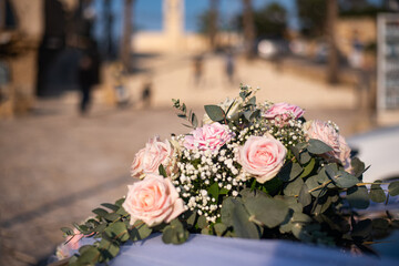 Romantic bouquet of delicate pastel roses on the background of old houses. Summer, fuzzy buildings, deserted. Car decoration for a wedding.