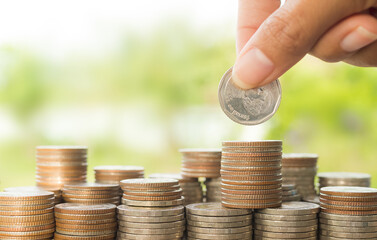 Plan save money 2021 concept. hand holding coin on stack coin money with green blur background.