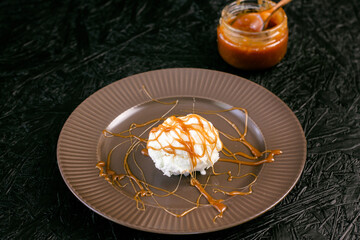 Fototapeta na wymiar Creamy ice cream with caramel on a plate on a dark background